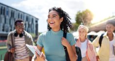 Estudantes universitários caminhando ao ar livre em campus, sorrindo e carregando cadernos e mochilas, representando o acesso ao ensino superior e novas oportunidades de estudo, como a lista de espera Prouni 2026.1