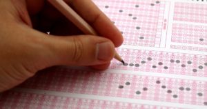 Gabarito do Enem impresso com alternativas A, B, C, D e E organizadas em colunas, com respostas marcadas a caneta, simulando o preenchimento oficial da prova em ambiente de exame.